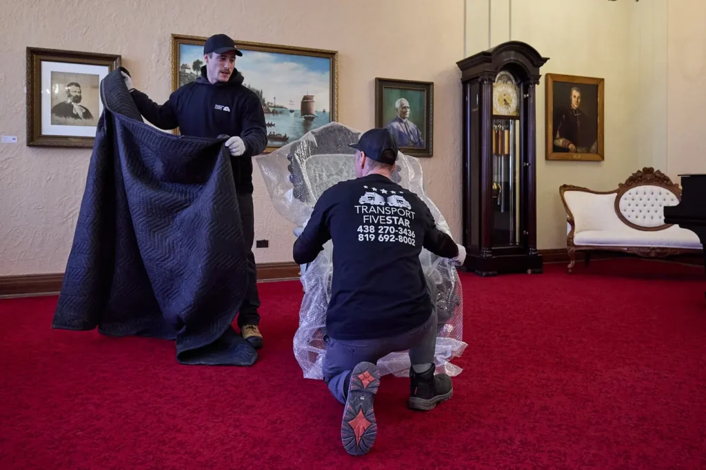 Deux déménageurs protègent un fauteuil avec une couverture avant le transport